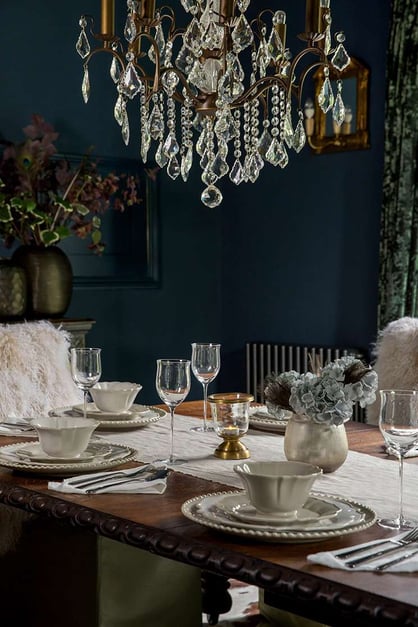 elegant dark royal blue dining room with chandelier and set table