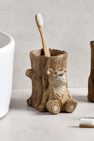 Wooden toothbrsh holder shaped like tree trunk with bear character