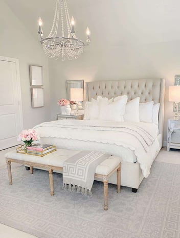 white bedroom with high headboard and chandelier 