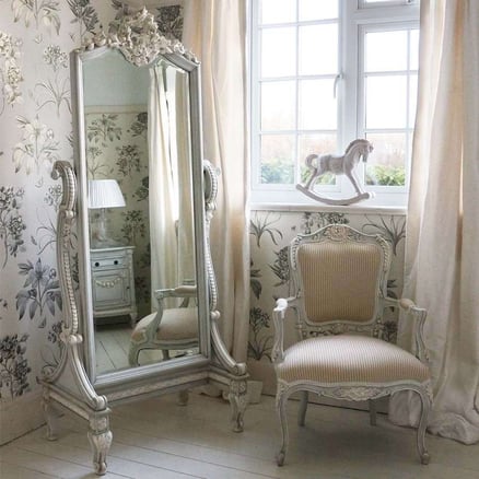 cream bedroom with matching chair and ornate full length mirror