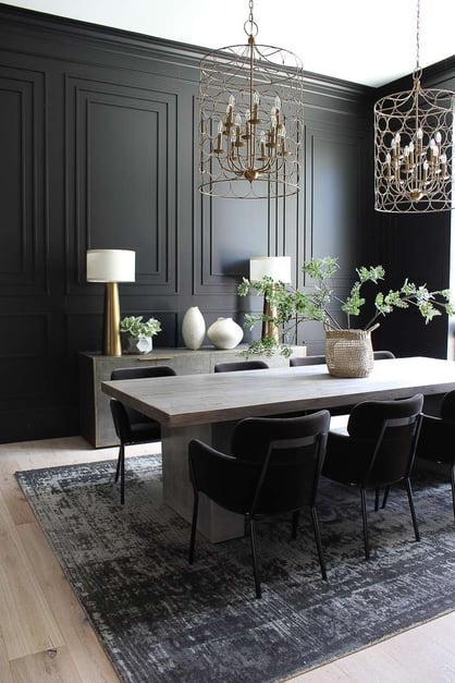 sleek dining room with black panneled walls and art deco inspired gold hanging light shades and side board.