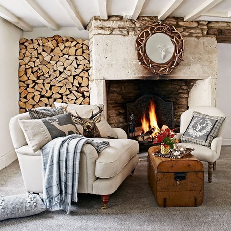 Cosy cabin-style living room with open fire and firewood log wall 