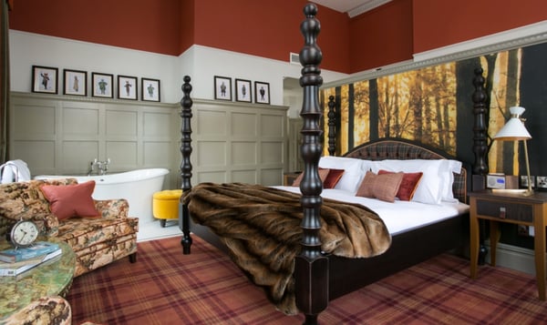 four poster bed, wood paneling and bathtub in the room